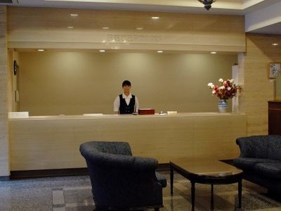 白いカウンターに、黒いベストを着た女性が立っている