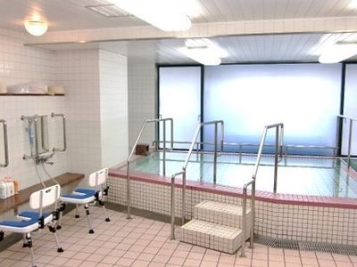 すりガラスが貼ってある浴室。浴槽の前には階段と手すりが設置されている