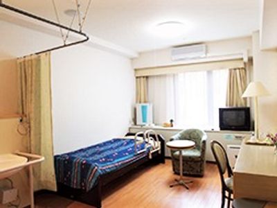 青いカバーが敷かれたベッドが置かれている部屋。隣にはカーテンで仕切られて洗面所がある