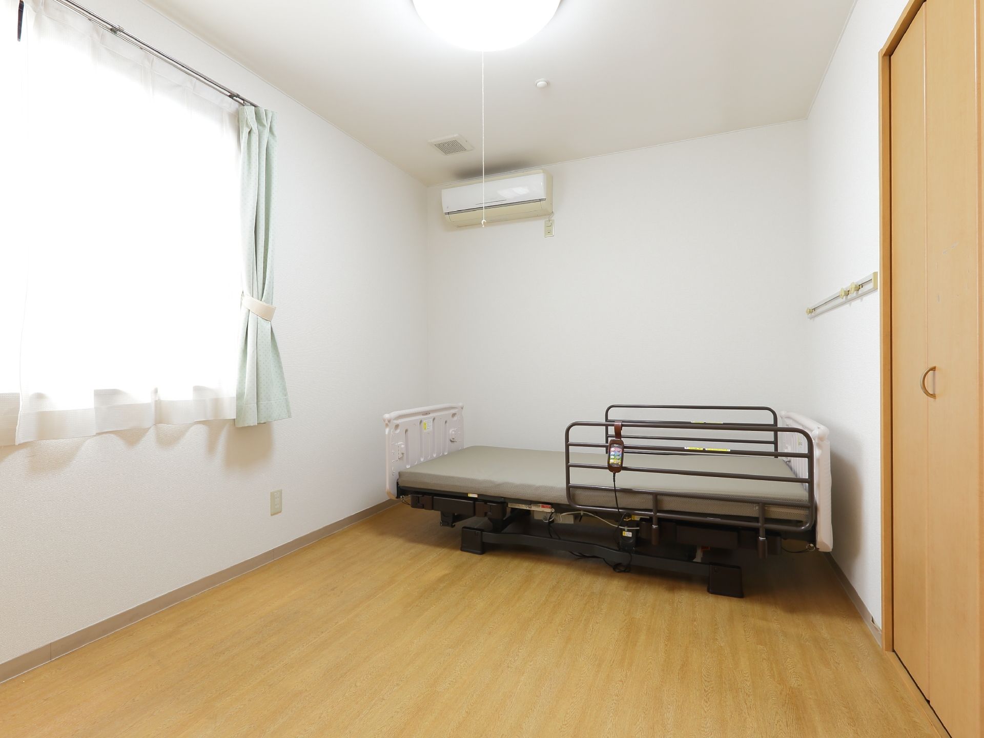 入居者一人ひとりに割り当てられる居室にはベッドが備え付けられている。転落防止の柵と点滴用の器具が付いた介護仕様。