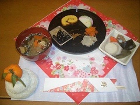 テーブルの上にお雑煮やおせち、煮しめといったお正月料理が並べられている。小ぶりな鏡餅も置かれている。