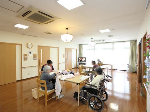 入居者の方々がこぞって何かの作業にいそしんでいる共用のリビング。天井の照明は埋め込み式と吊り下げ式が組み合わされている。