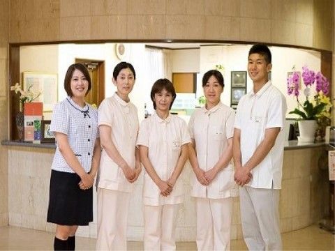 制服を着た男性一人と、女性四人がカウンターの前で写っている写真
