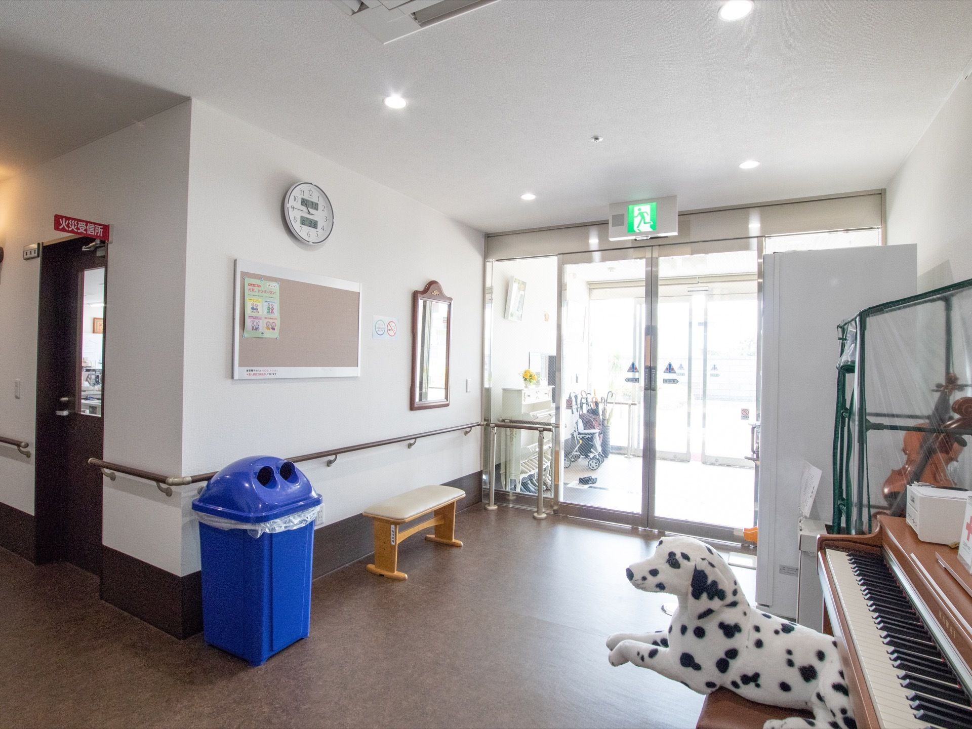 エントランスは明るく広々としていてピアノやバイオリン、犬のぬいぐるみなどが置かれている。壁には時計や鏡が掛けられている。