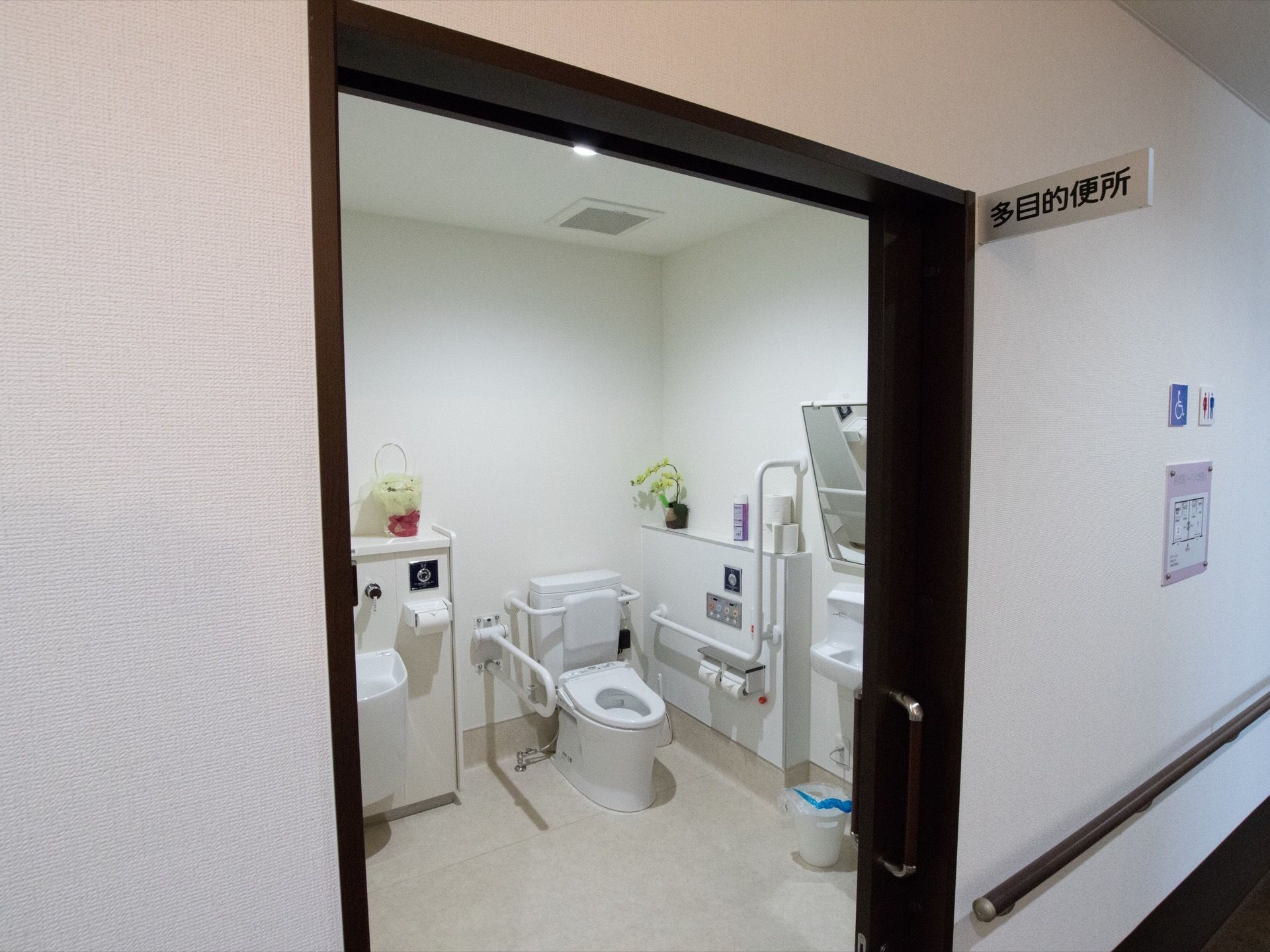 多目的便所と書かれた白いプレートがドアの上部に掲げられている。入り口は幅広のスライド式ドアとなっている。