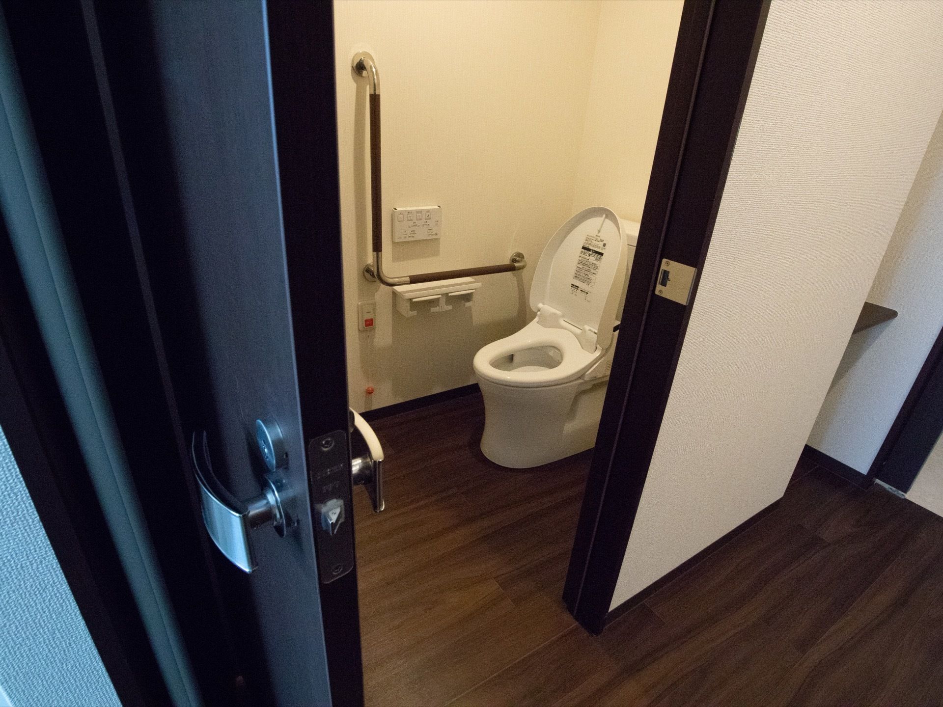 居室からトイレへは段差なく行くことができる。トイレのドアはシックな色合いで、大きく開くタイプとなっている。