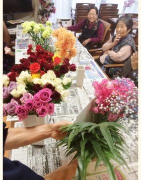 新聞紙が敷かれたテーブルの上にある、何種類かの色とりどりの花
