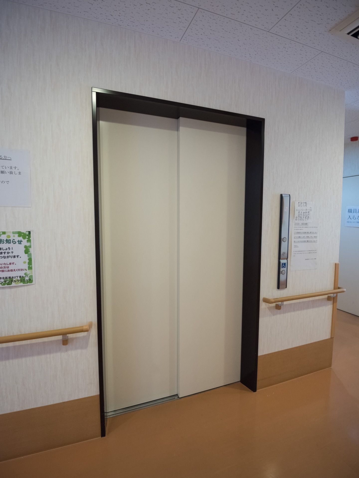 廊下の途中にエレベーターがある。車椅子にも対応した幅のある造りになっていて、近くの壁には手すりが付いている。