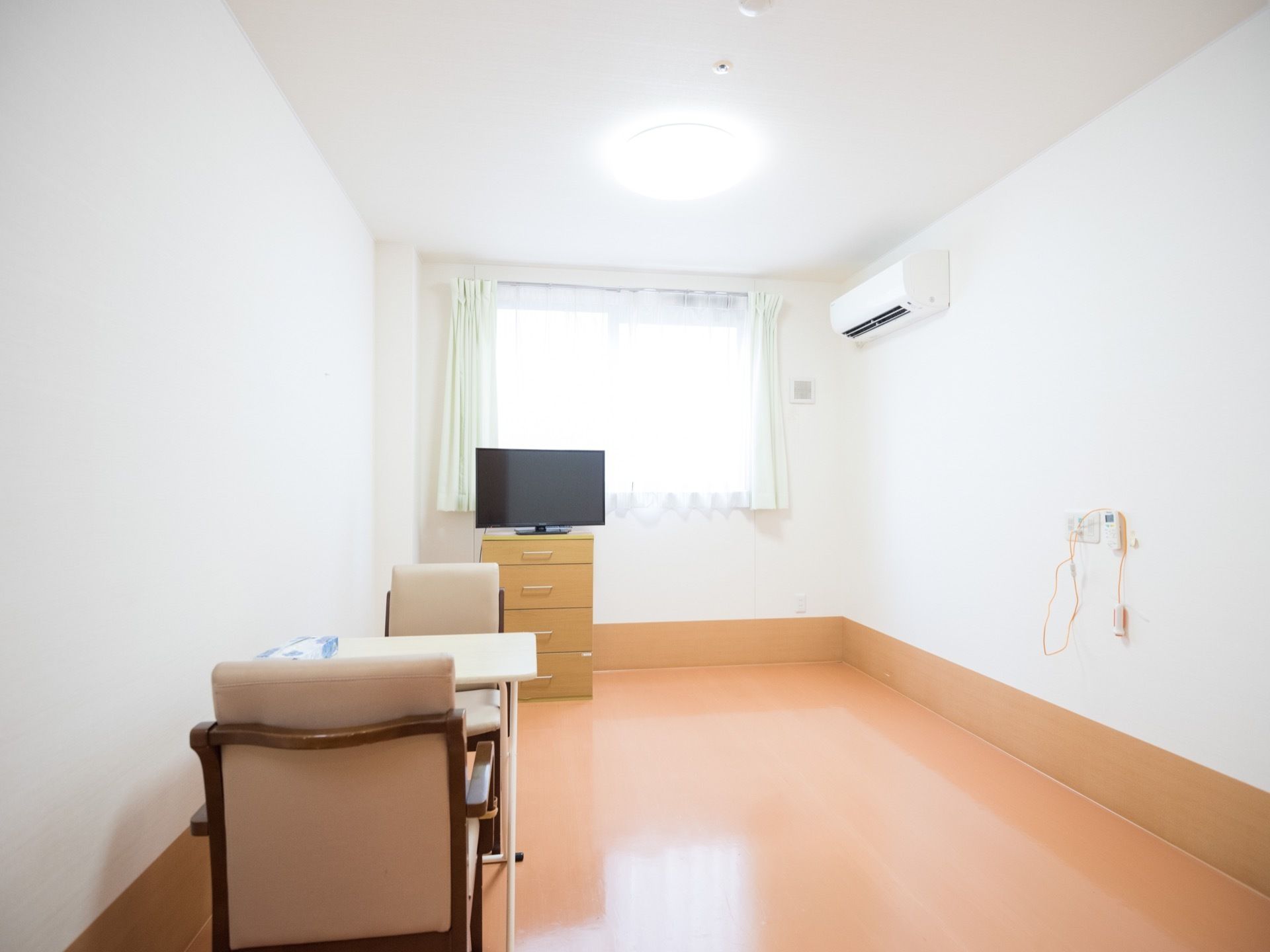 居室にはテレビや椅子、テーブル、エアコンがある。日当たりが良いので、生活しやすくなっている。