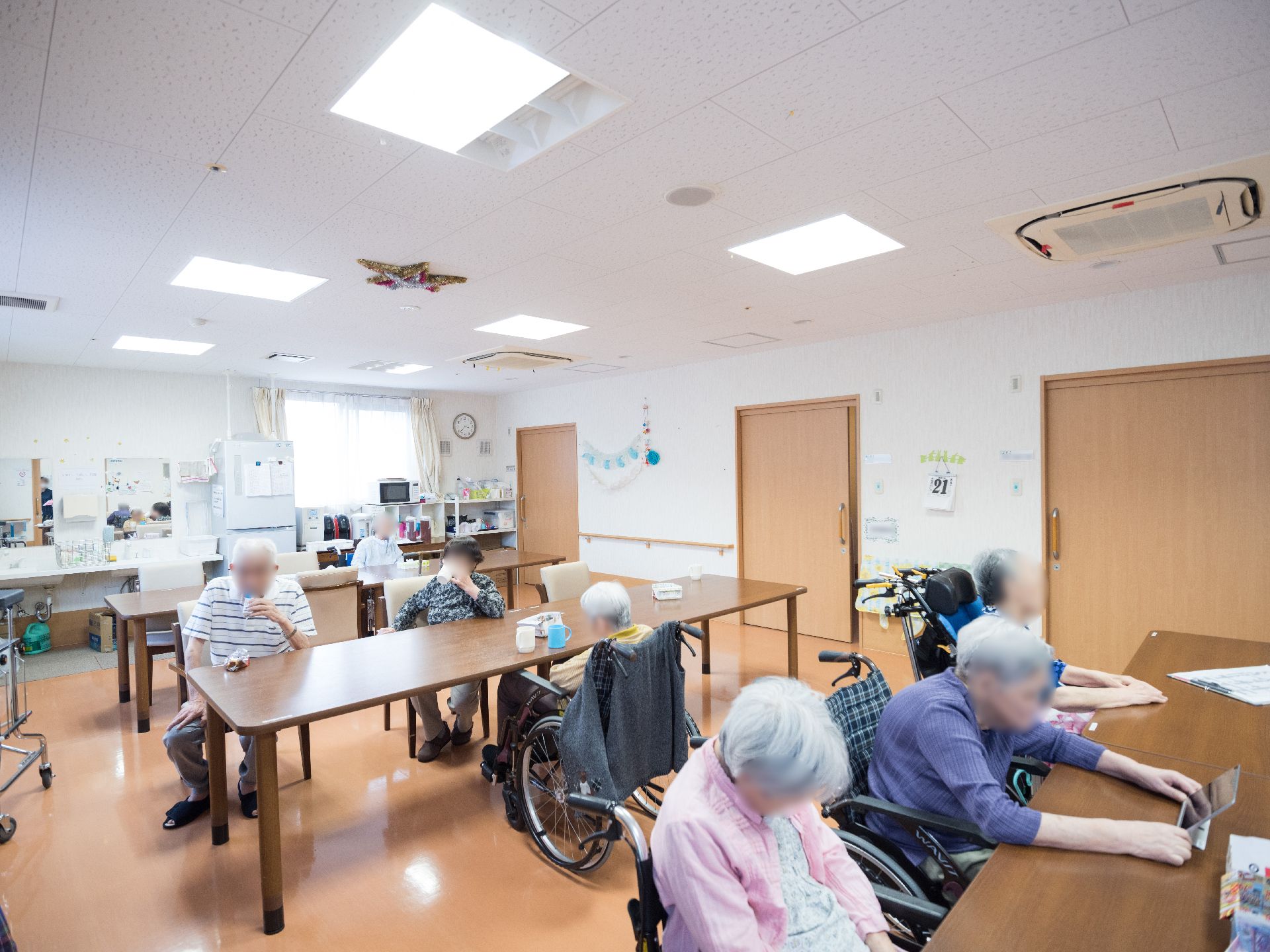 テーブルが３列並んでいる食堂に集まっている入居者様たち