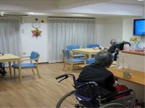 壁掛けテレビが設置され、その近くにテーブルや椅子が置かれている食堂