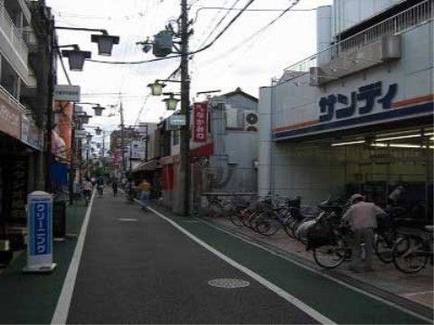 電柱の上部に該当が設置され、多くの店が並んでいる商店街