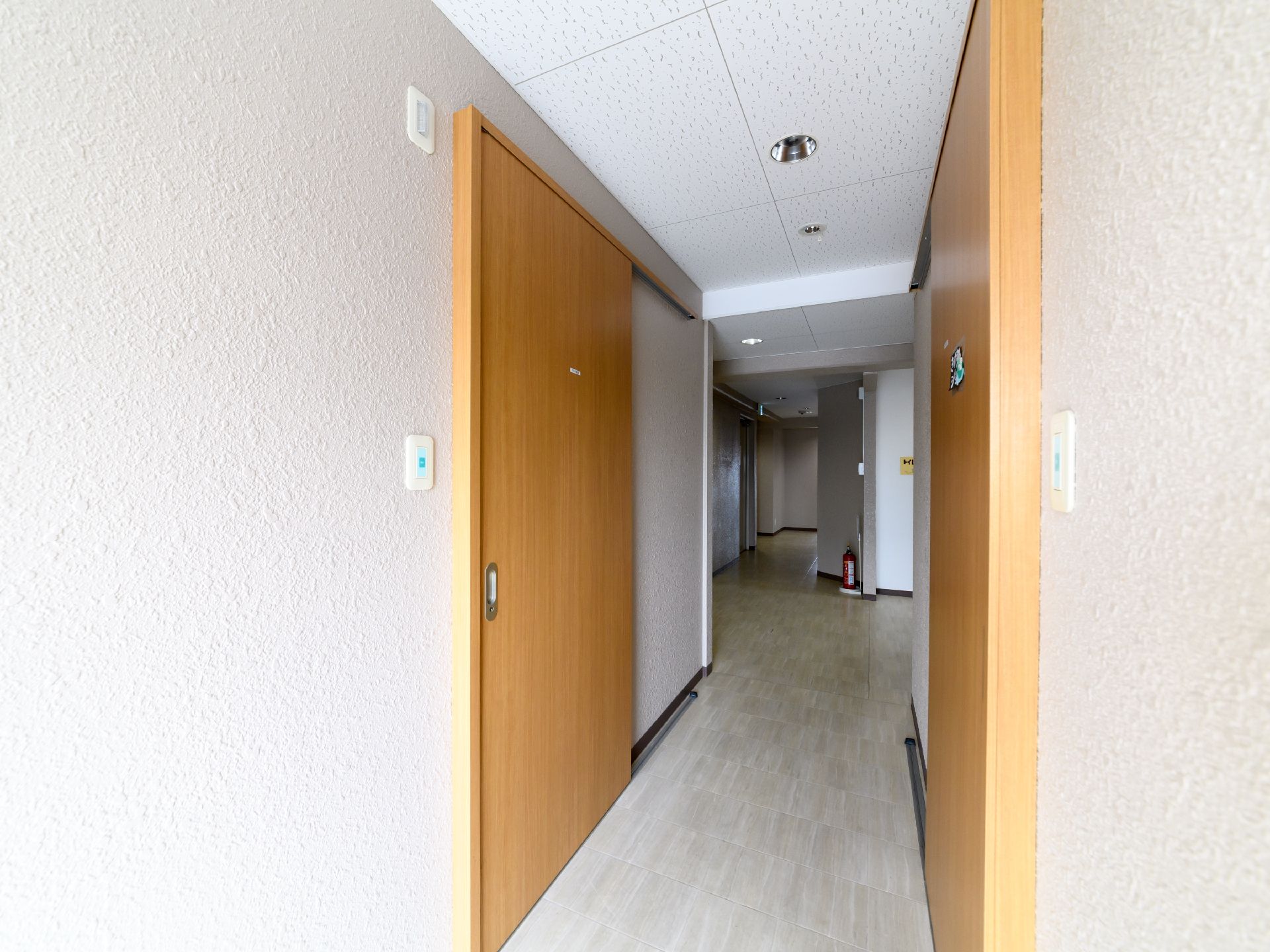 部屋のドアは引き戸タイプで、廊下からはバリアフリーの床になっているので出入りしやすい。通路には消火器が設置されている。