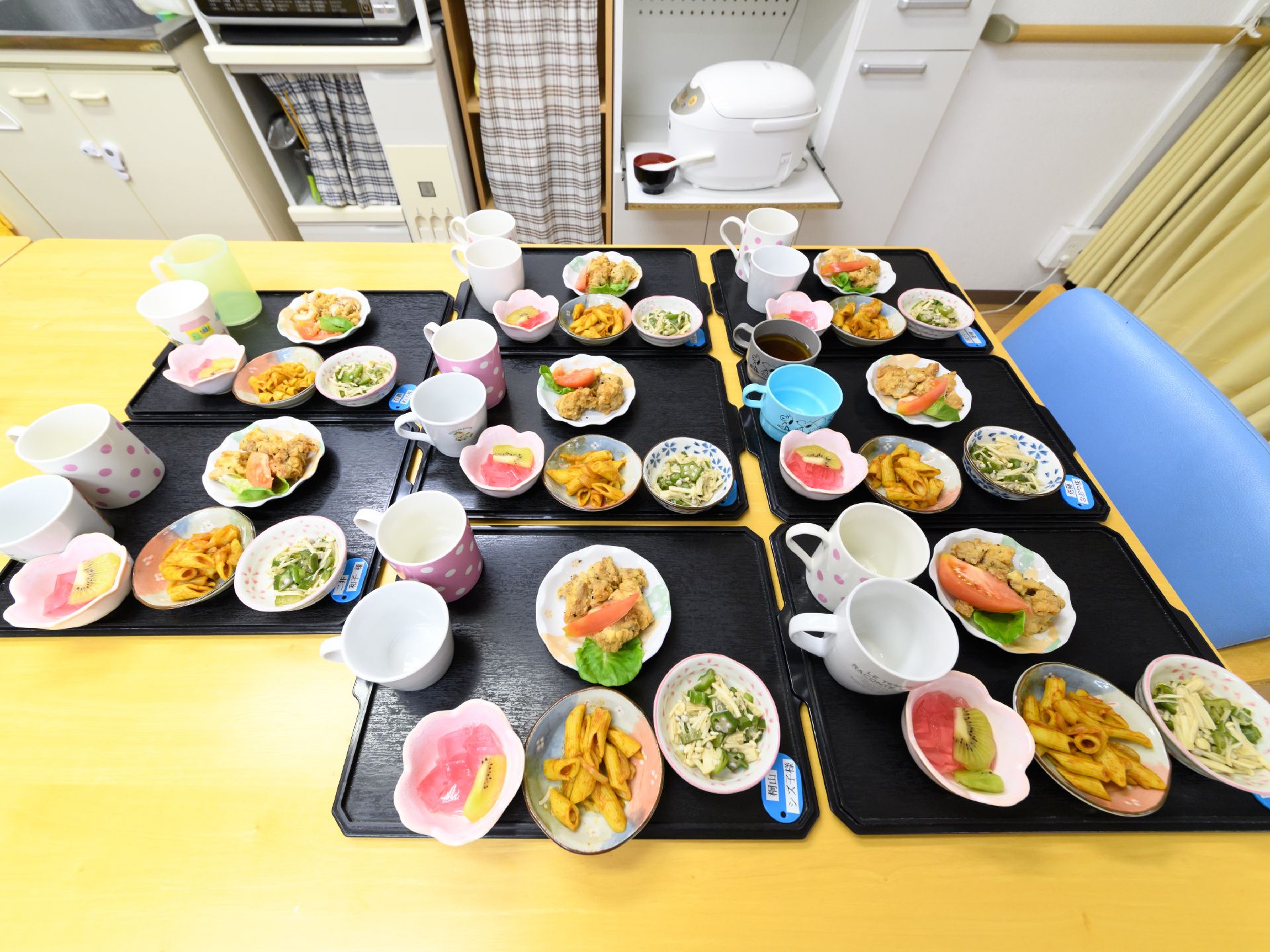 食事は一人ずつ黒いお盆の上にのせて配膳される。青いカードには入居者様の名前が印字されたシールが貼ってある。