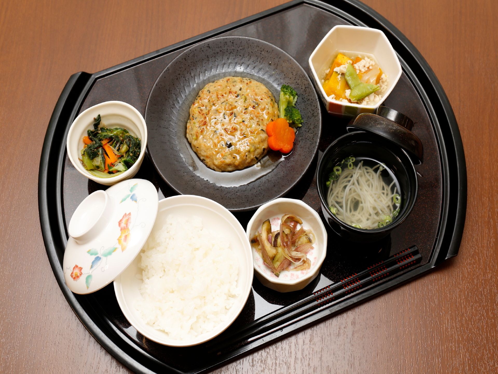 施設の食事の一例である。プレートには主食や汁物をはじめ、主菜、副菜が三種類、そしておはしが置かれている。