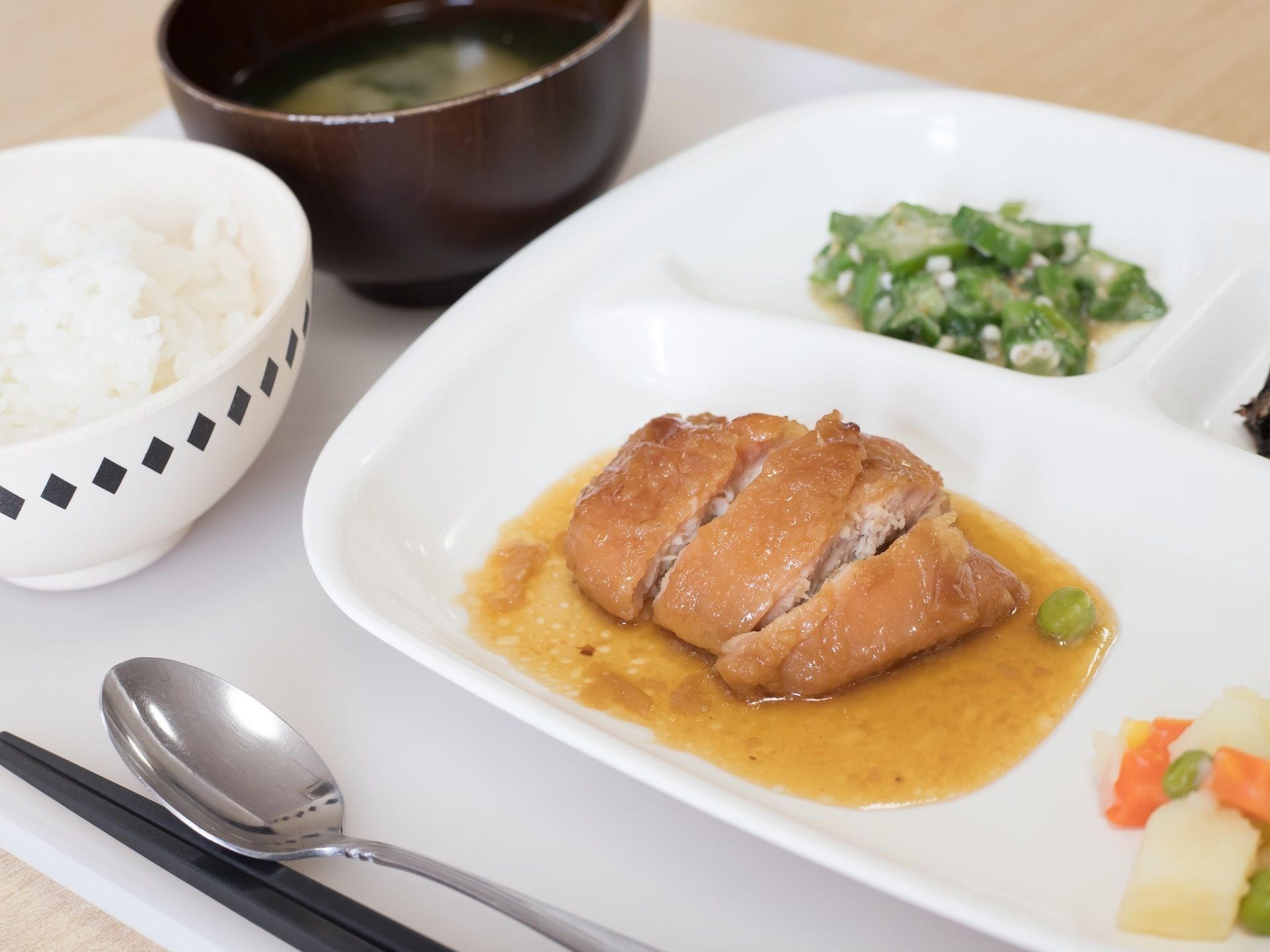 食事の一例である。主食や汁物、栄養価が考慮された品々がプレートに取り分けられている。お箸とスプーンが添えられている。