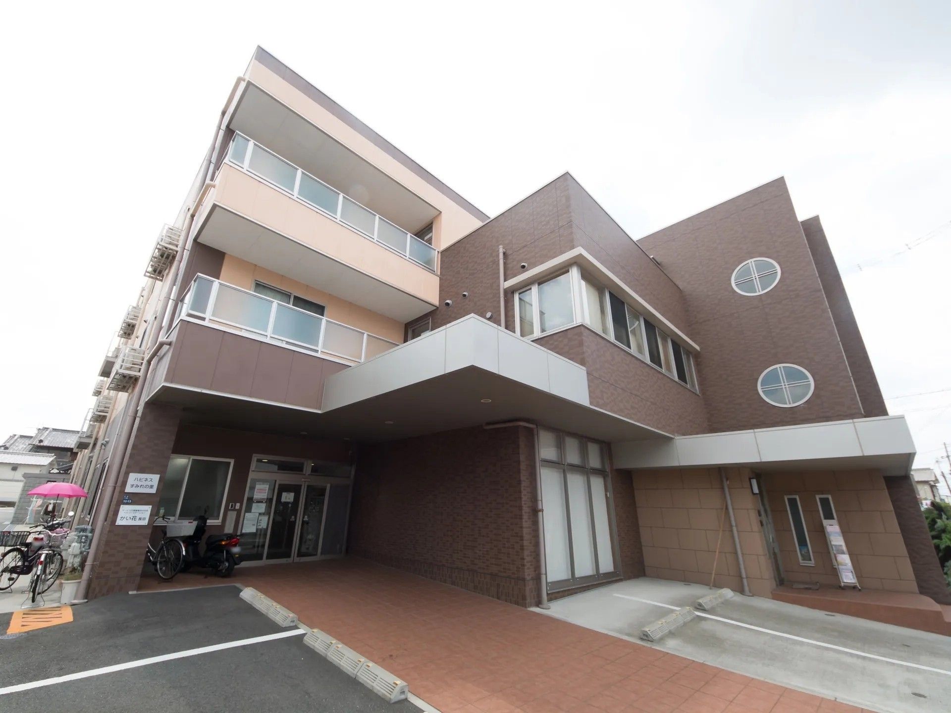 ダークブラウンを基調とした外壁で、落ち着いた感じの３階建ての建物である。駐車場が隣接しており、アクセスが便利である。