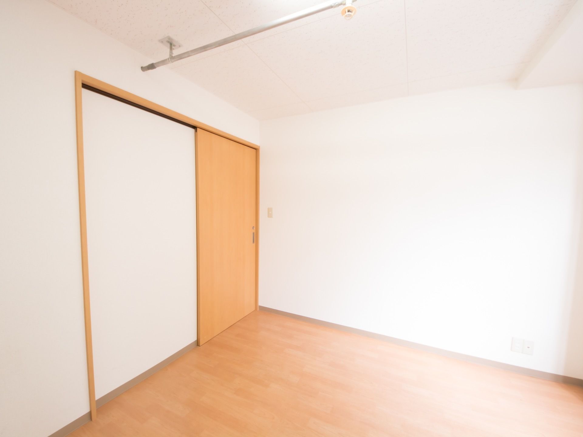 フローリングの床に、同系色の引き戸を設置した部屋がある。天井には、細い銀色のパイプを設置したつくりをしている。