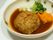 食事の1つであるハンバーグが大きく映っている。丸い器に盛り付けられて人参とブロッコーリーがそえてある。