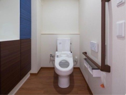 トイレは広く、床や壁の一部がシックな色合いの木目調である。壁には手すりや、緊急コール用のボタンがある。