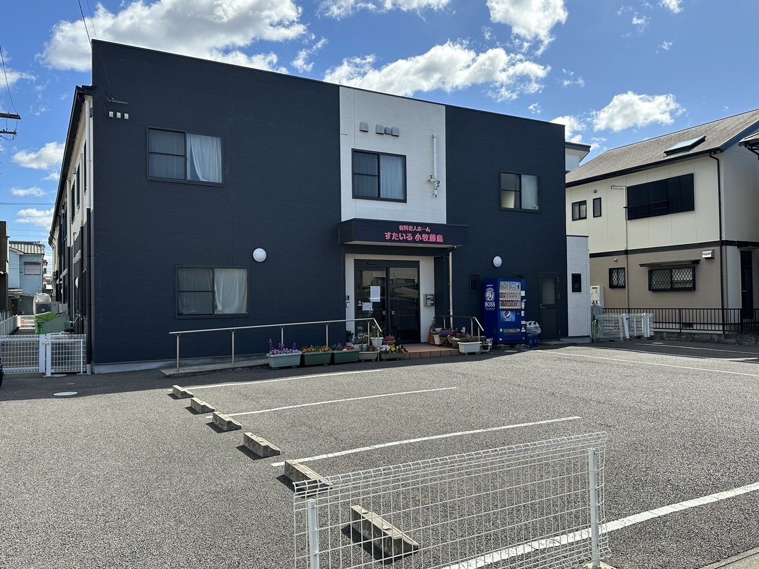 黒と白の2色で彩られた建物がある。入口は階段とスロープがあり、いずれも手すりがついている。ドアの横には自動販売機がある。