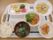 両側に取っ手が付いたお盆の上に、いくつかおかずとサラダが用意され、ご飯と味噌汁が並んで置かれている。