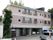 目の前と1階の一部が駐車場になっており左側から入館する。建物は3階建であり左下の壁に施設名の入った看板が出ている。