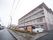 見晴らしの良い場所に建てられた施設。施設の入り口に大きな看板が設置されている。道路に面したところには草花が植えられている。
