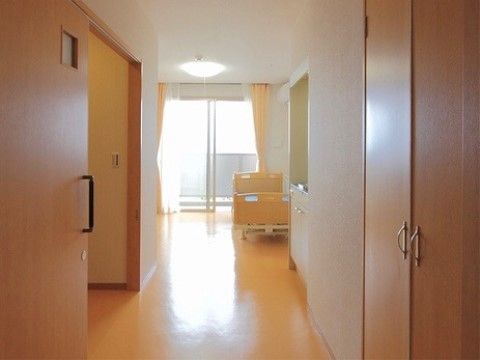 居室にはベッド、トイレ、ミニキッチン、収納スペースが設置されている。ガラス引き戸が設けられ、壁と天井は白色である。