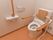 背あてとひじ掛けが追加された洋式トイレが設置されている。壁には手すりや操作パネル、ナースコールが取り付けられている。