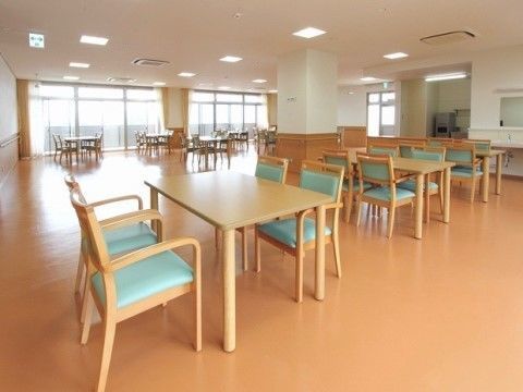 窓の近くにテーブルと椅子が置かれている、広いスペースのある食堂