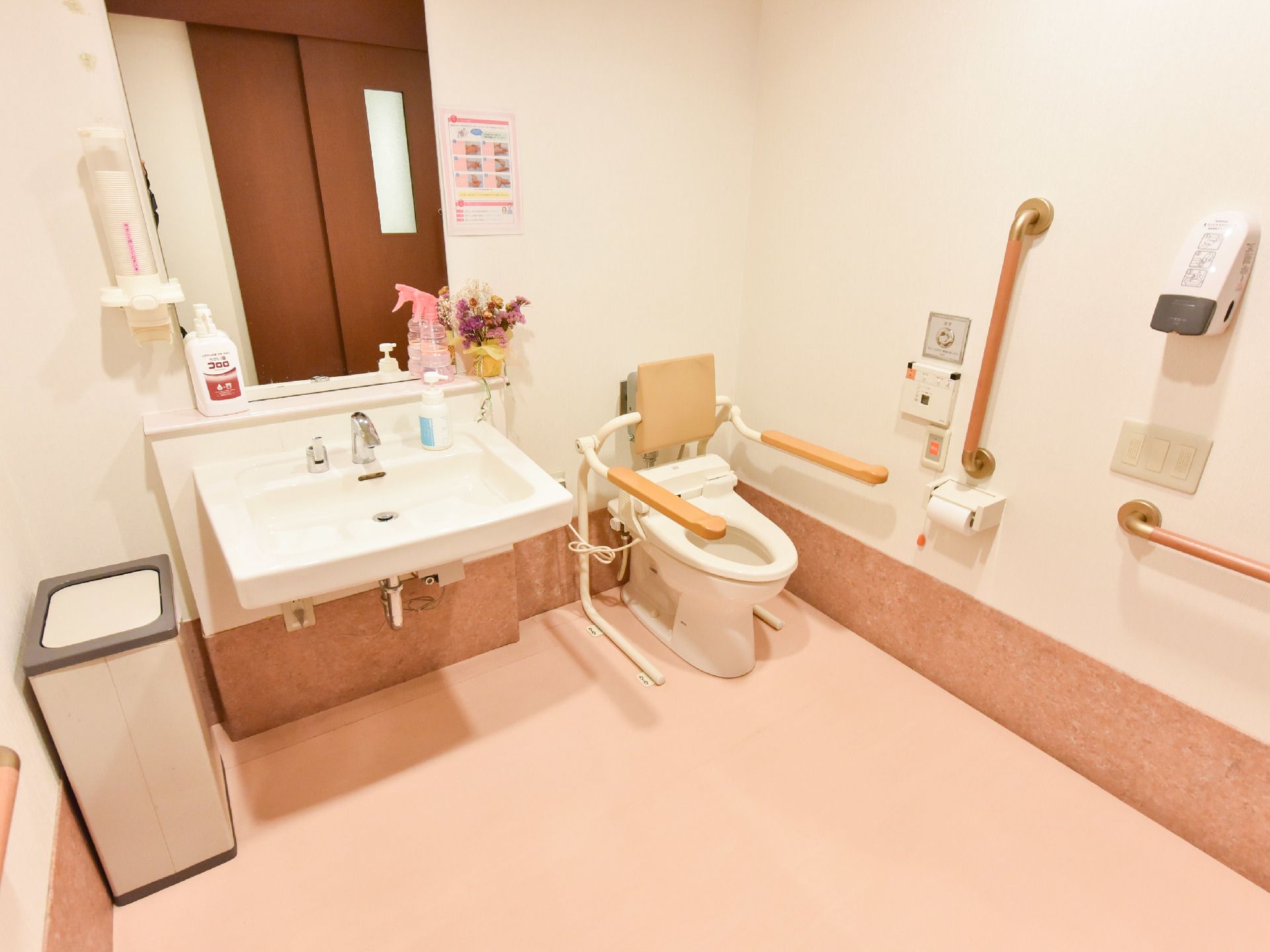 中央やや左に洗面がついており、目の前には大きな鏡がある。左側にゴミ箱があり右手のウオッシュレット式トイレには左右に手すりがついている。