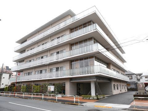 白い外壁とベランダの曇りガラスが高級感を与える施設外観。