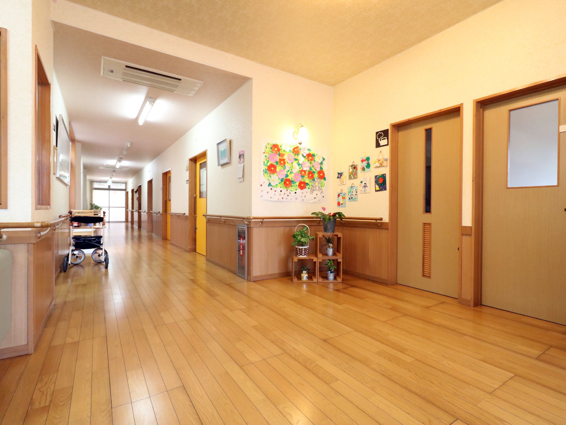 廊下は上部がクリーム色で下部が木目調の壁になっており、手すりが敷設されている。空調が設備されおり、床はフローリングになっている。