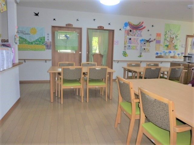 各テーブルに、緑色の座面がついた椅子が４脚ずつ置かれている食堂