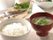 テーブルの上に、手前はご飯と味噌汁、その上に焼き魚のメインおかずと小鉢を配膳している。毎日、温かい食事が味わえる。