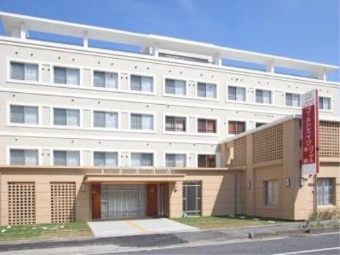 道路に面した４階建ての建物である。白い側面にたくさんの窓が並んでいる。日あたりの良い立地の施設である。