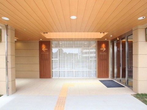 オレンジの天井の屋根付きのエントランスは、ゆったりとした贅沢な空間である。点字ブロックを設置し、ガラス張りのドア前にマットを敷設している。