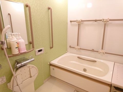 体の疲れを安全に癒せるよう、手すりを設置している。モスグリーン色の壁紙はリラックス効果があり、心地よい入浴タイムを過ごすことができる。