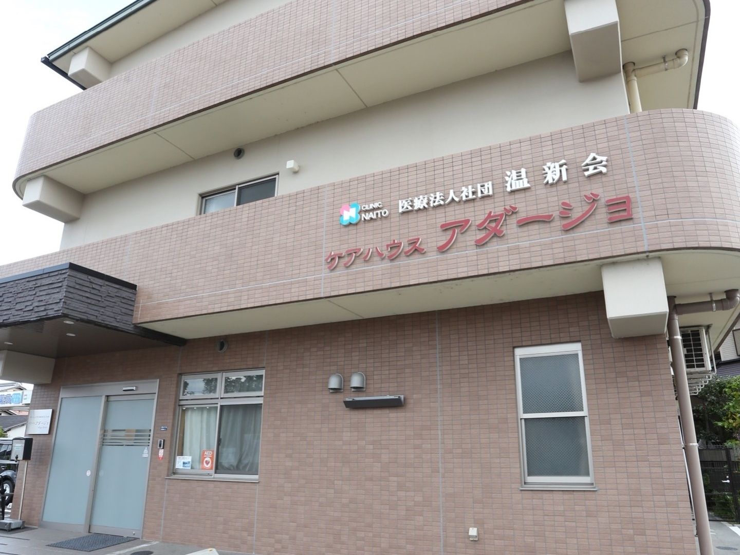 施設は3階建てで、茶色を基調とした外壁となっている。玄関のそばには、1台分の駐車スペースが設けられている。