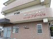 施設は3階建てで、茶色を基調とした外壁となっている。玄関のそばには、1台分の駐車スペースが設けられている。
