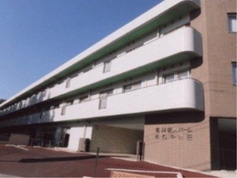 白色と一部茶色を基調とした外壁の横に長い３階建ての施設外観