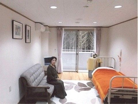 居室の壁際に置かれたソファに腰かけている女性入居者様