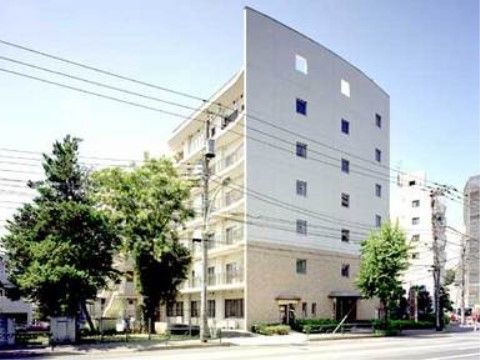 ベージュ色と白色の外壁の、道路沿いに立地している６階建ての施設全景外観