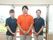 3名のスタッフが室内で映っている。男性１名女性2名で色違いのポロシャツを着ている。ズボンはお揃いの物を着ている。