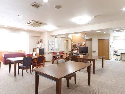 窓から陽が良く差し込んでいる部屋にはテーブルと椅子が数台ある。窓辺にはソファーがある。壁に折り紙の作品がある。