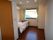 １人用居室の一例。入口横にトイレがある。居住スペースには介護用ベッドが窓際に置かれている。エアコンが完備されている。