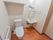 白を基調とした清掃の行き届いた清潔感のあるトイレである。洗面台が併設され、壁には鏡と収納棚が取り付けられている。