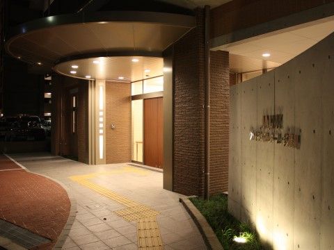 玄関前にある屋根に取り付けられたダウンライトで照らされている夜間の玄関