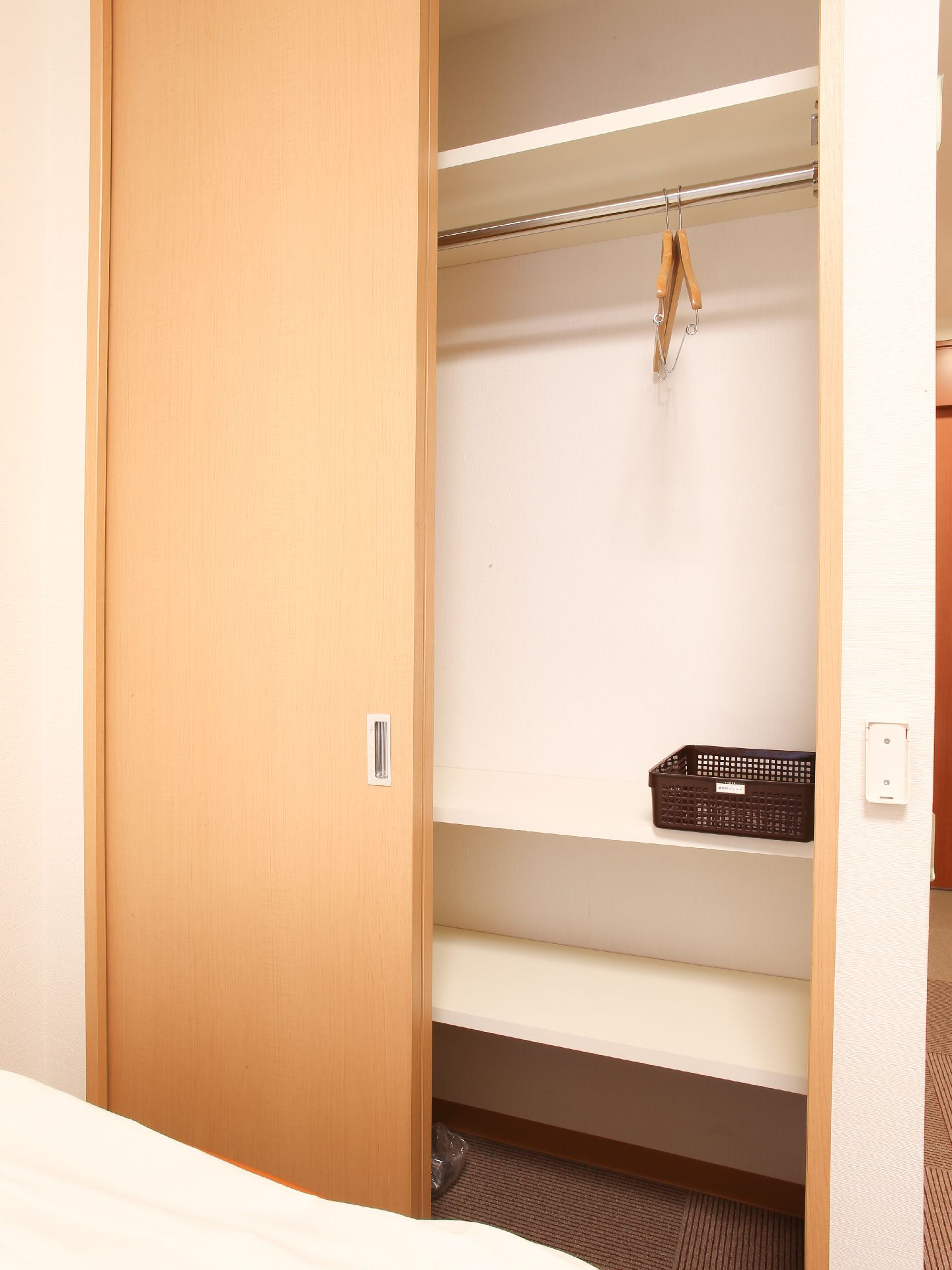 木目調の優しい色合いの建具になっている。また、収納もハンガーパイプも設置してあり、荷物も置けるようになっている。